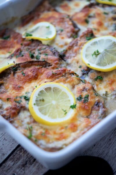 pieces of eggplant francaise in a white dish with lemons