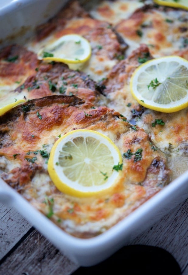 pieces of eggplant francaise in a white dish with lemons