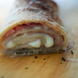 a close up of a cooked ham and provolone stromboli