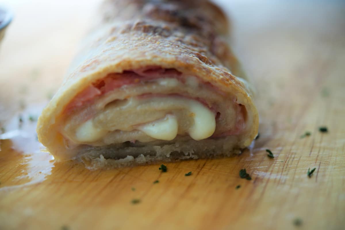 a close up of a cooked ham and provolone stromboli