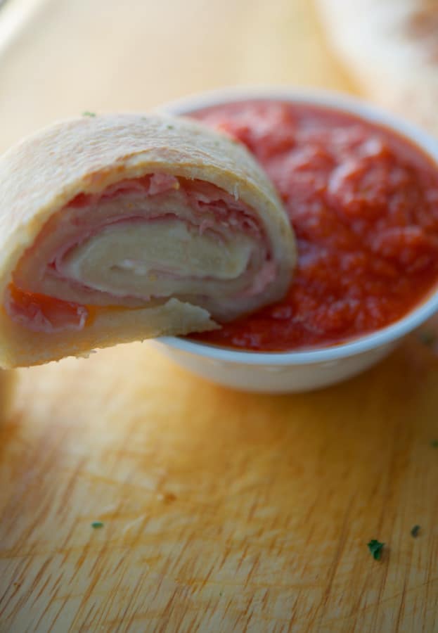 a slice of a stromboli in dipping sauce