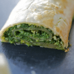 a close up of savory spinach strudel on a slate plate