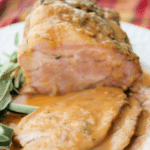 crock pot apple cider pork half sliced on a white plate