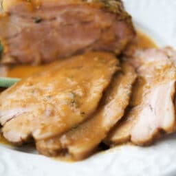 a close up of apple cider pork sliced on a white plate