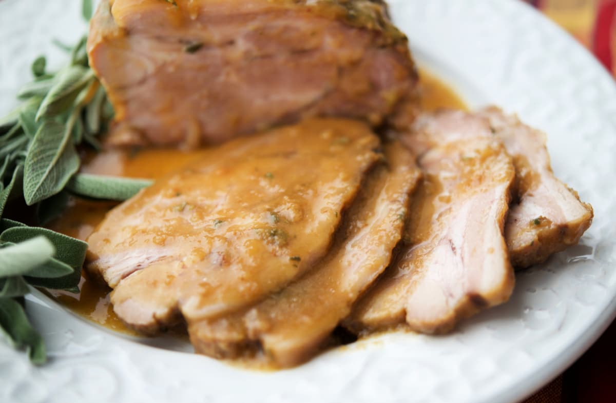 a close up of apple cider pork sliced on a white plate