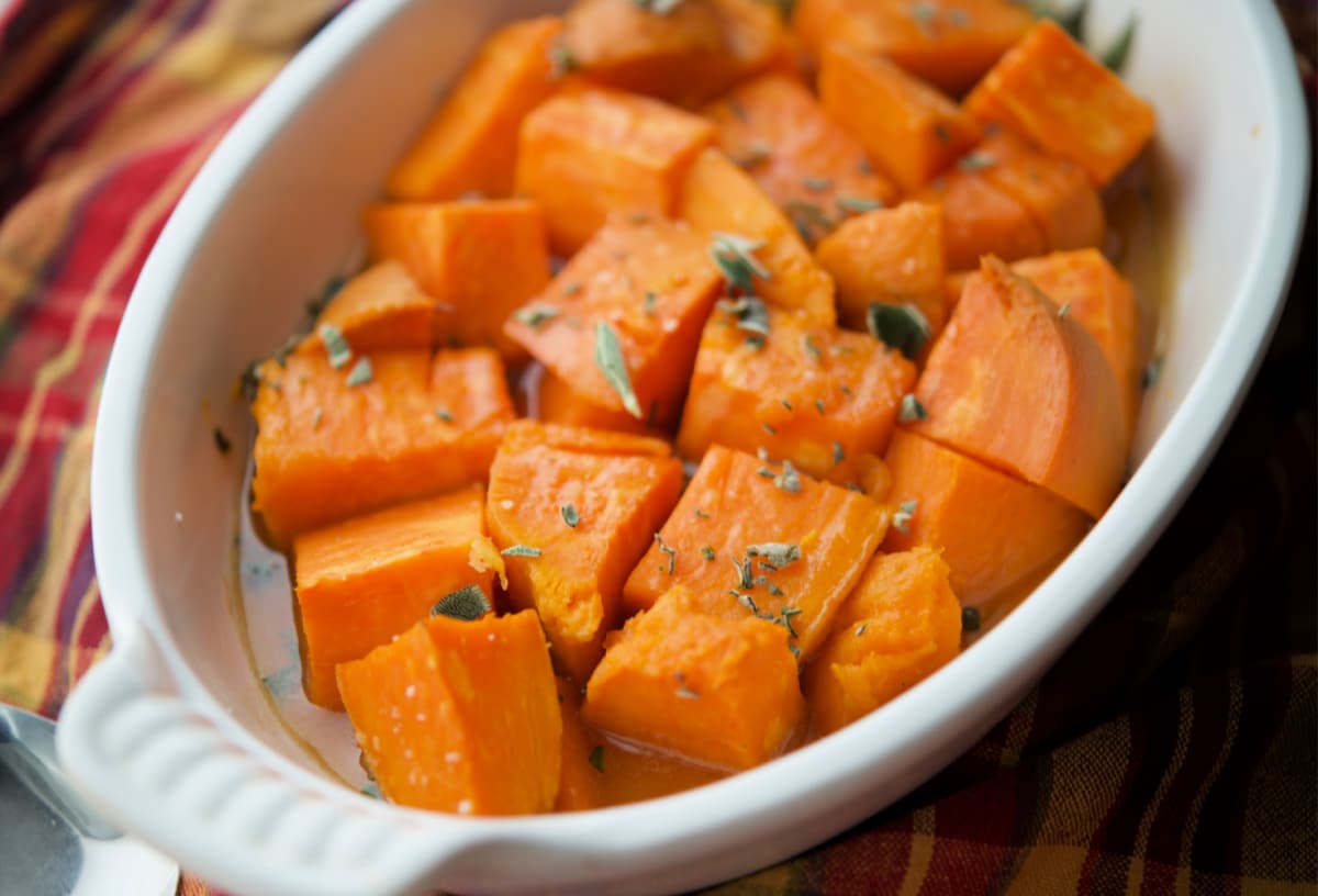 sweet potatoes with maple glaze in a white casserole dish