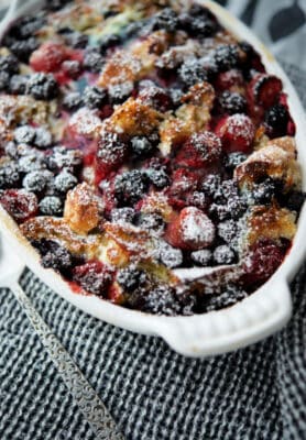french toast casserole with mixed berries in a white casserole dish