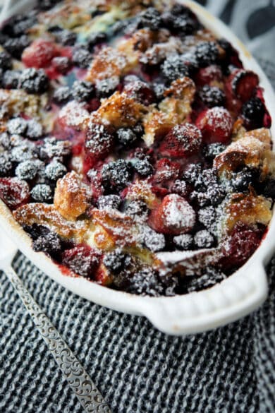 french toast casserole with mixed berries in a white casserole dish