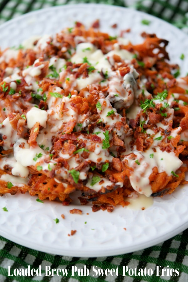 a plate of sweet potato fries with cheese sauce and bacon