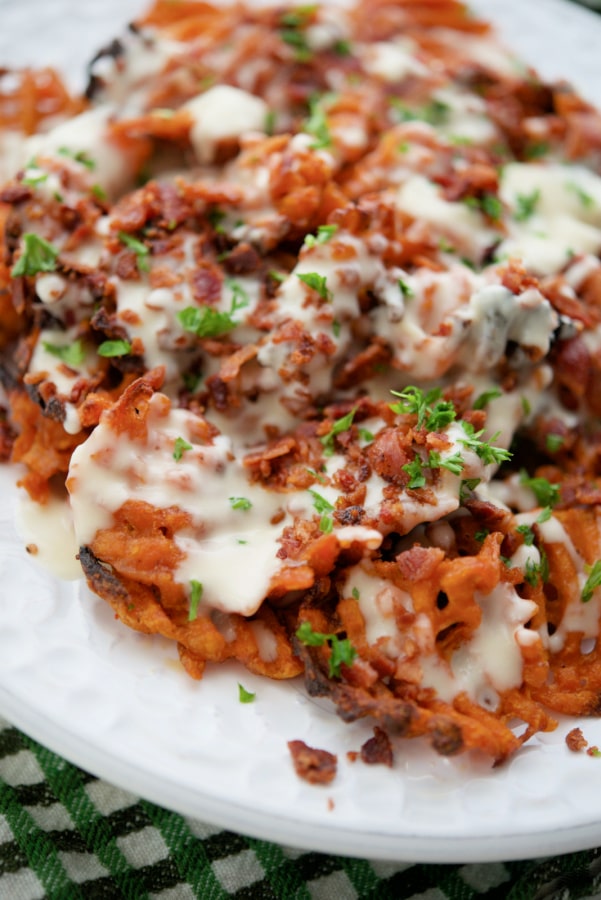 sweet potato waffle fries with cheese sauce and bacon on a plate