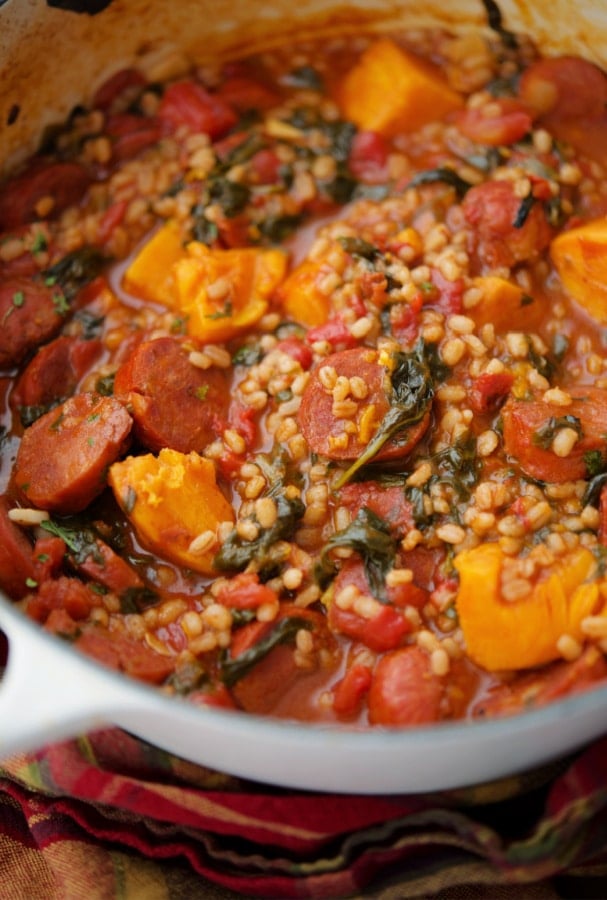 portuguese chourico, sweet potato and spinach stew with barley in a white Dutch oven