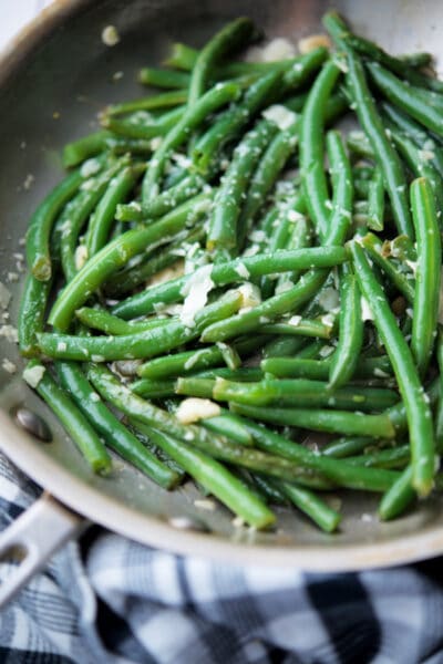 a skillet with cooked green beans and garlic