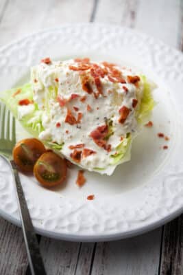wedge salad with parmesan peppercorn buttermilk dressing on a white plate