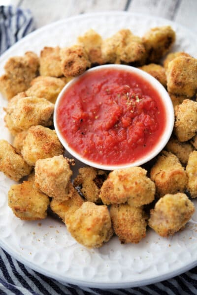 italian baked chicken nuggets on a white plate with a dish of marinara sauce