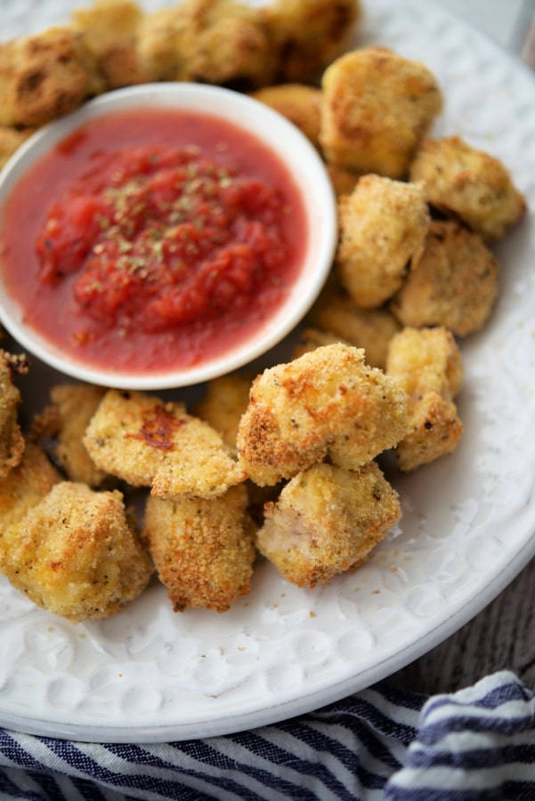 chicken nuggets on a white plate with tomato sauce