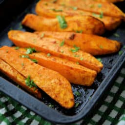a close up of roasted sweet potato wedges in a small roasting pan