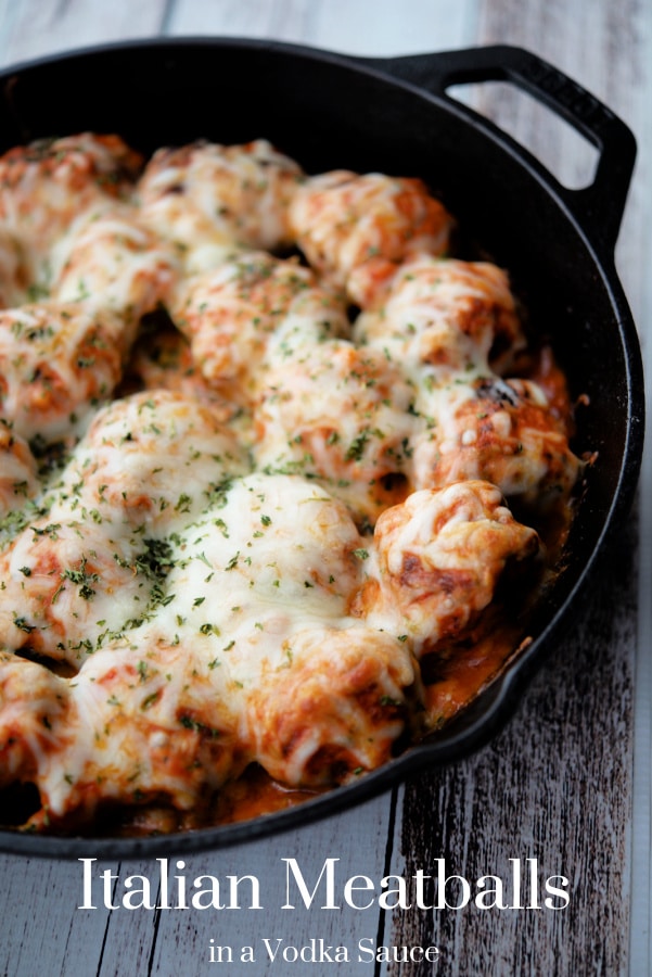 meatballs topped with cheese in a cast iron skillet