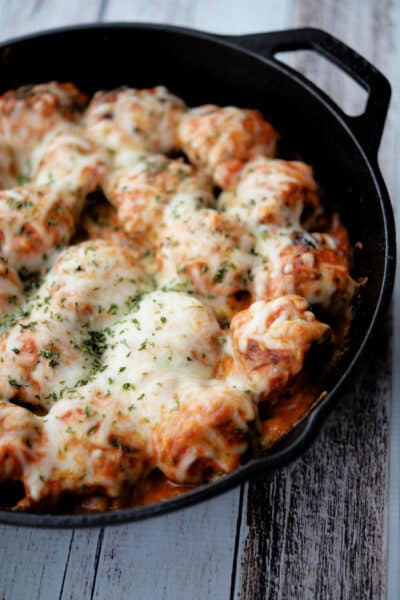 meatballs with vodka sauce and melted cheese in a skillet