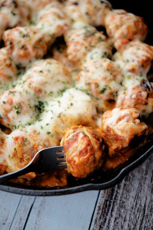 italian meatballs in a skillet with one on a fork