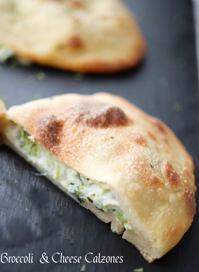 broccoli and cheese calzone cut in half on a gray tile