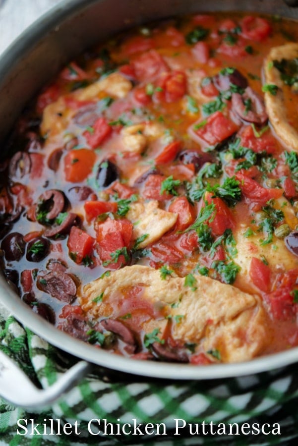 a skillet with chicken tomatoes and olives