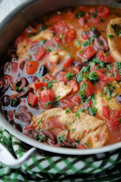 chicken puttanesca with tomatoes, olives and capers in a skillet