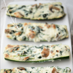 spinach mushroom and ricotta stuffed zucchini boats on a white plate