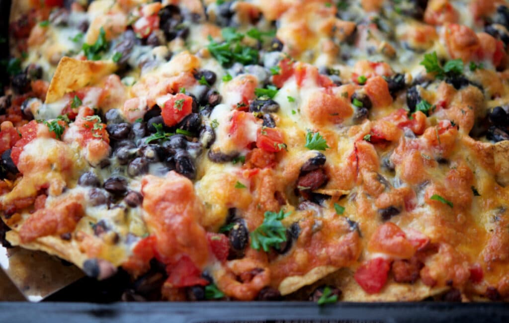 a close up of chourico nachos on a sheet pan