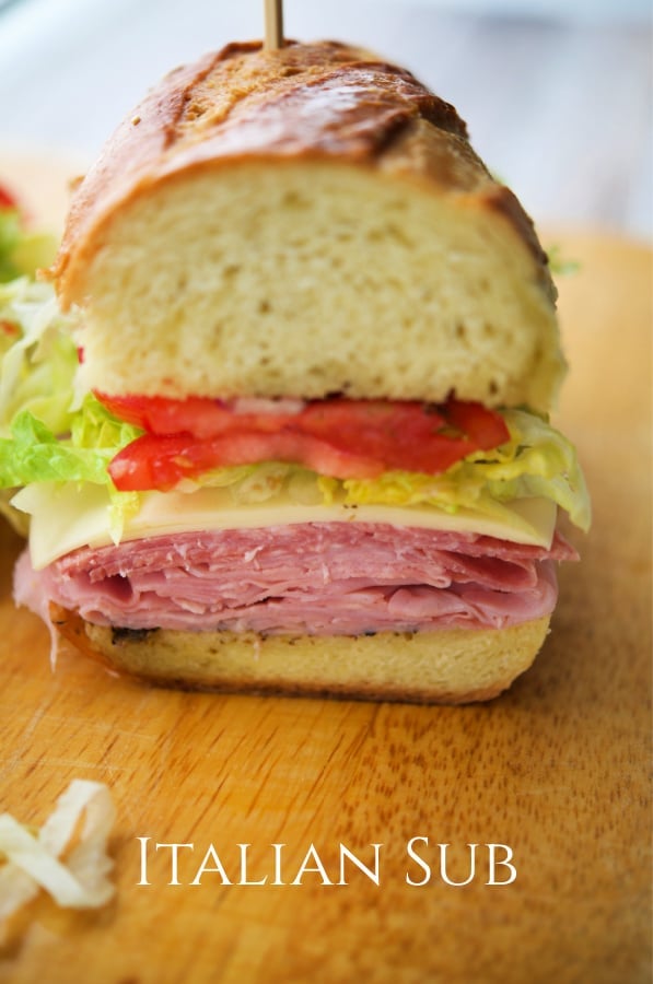 a close up of an Italian sub on a wooden cutting board