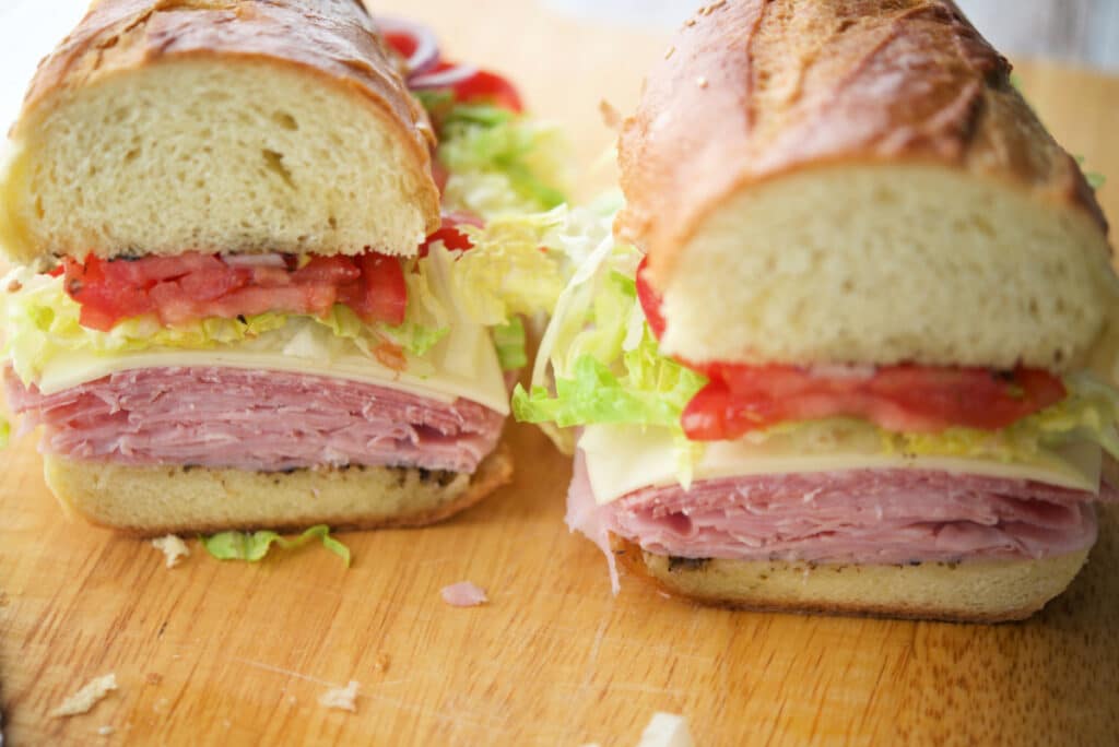 two pieces of an italian sub sandwich on a wooden cutting board