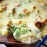a close up of broccoli and cauliflower with a gorgonzola cheese sauce on a wooden spoon