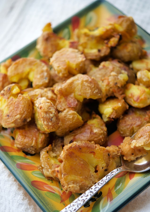 parmesan smashed potatoes on a plate with a spoon