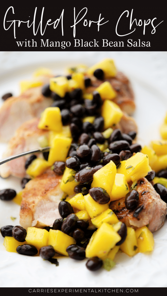 sliced pork chop on a white plate with mango black bean salsa