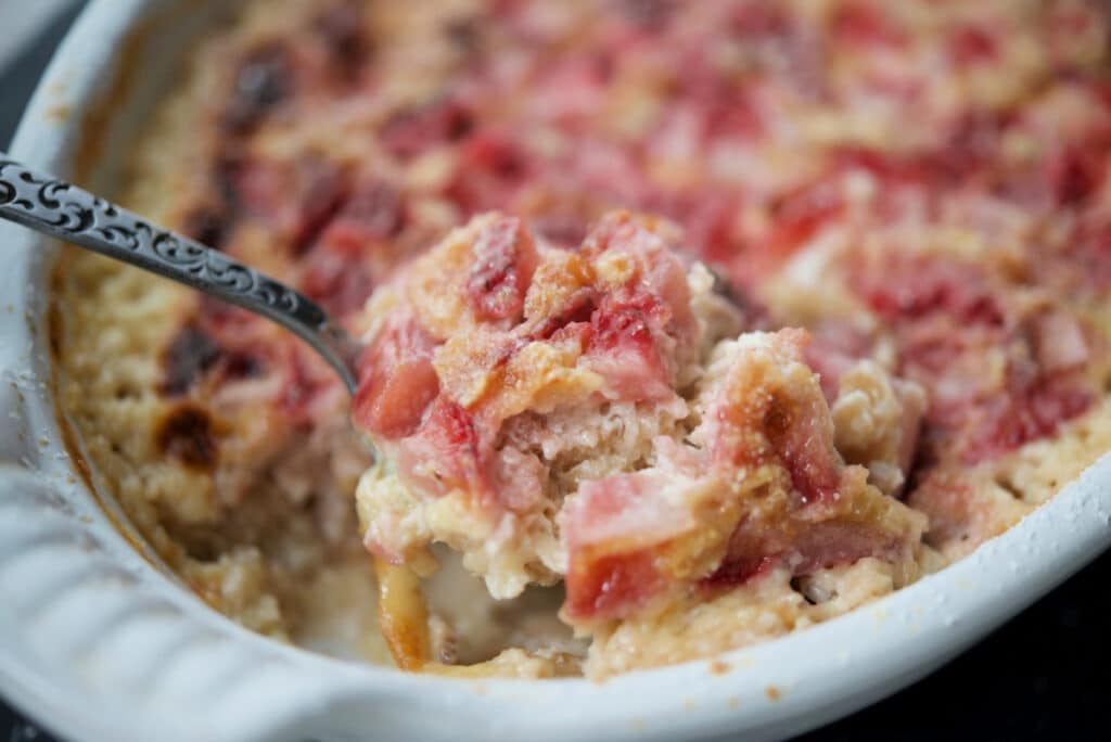 a close up of baked oatmeal with strawberries on a spoon