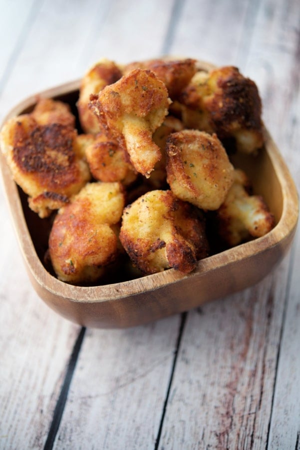 a wooden bowl filled with fried cauliflower milanese