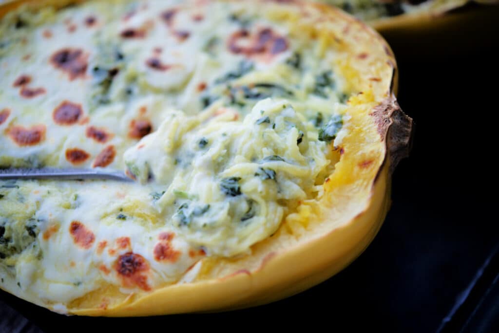 a close up of spinach alfredo spaghetti squash on a spoon