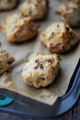 bacon and cheddar drop biscuits on a parchment paper lined sheet pan