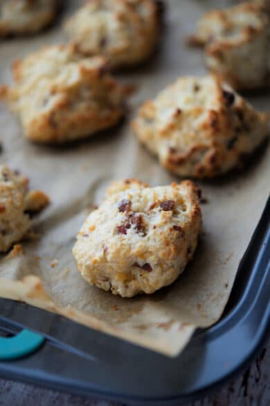 bacon and cheddar drop biscuits on a parchment paper lined sheet pan