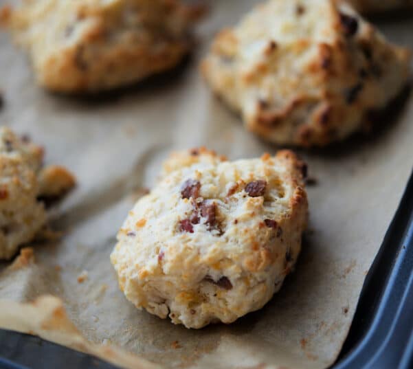 bacon and cheddar drop biscuits on a parchment paper lined sheet pan