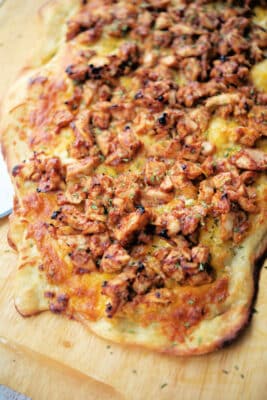 bbq chicken flatbread pizza on a wooden cutting board