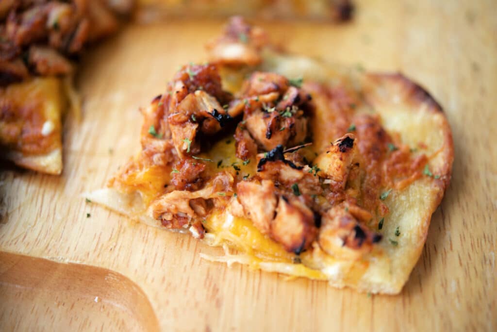 a slice of bbq chicken flatbread on a cutting board