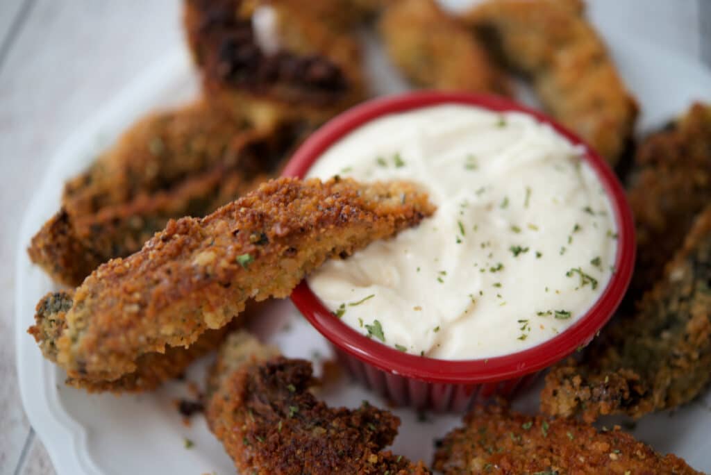 a close up of a mushroom fry dipping into a garlic aioli