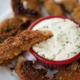 a close up of a mushroom fry dipping into a garlic aioli