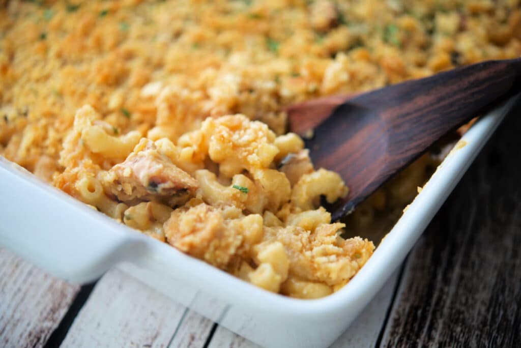 a close up of bbq chicken mac and cheese in a dish with a spoon