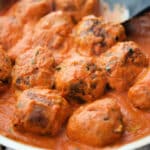 a skillet with zucchini meatballs in a pink sauce