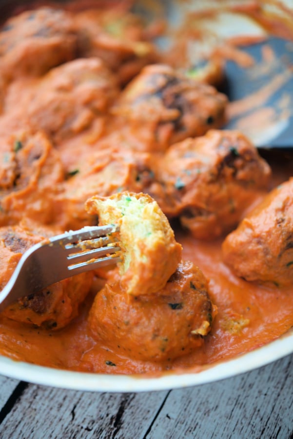 a zucchini meatball in sauce on a fork