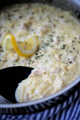 lemon garlic orzo chicken in a skillet with a black spoon