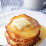 a stack corn pancakes on a plate with melting butter and syrup