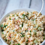 amish macaroni salad in a white bowl on wood planks