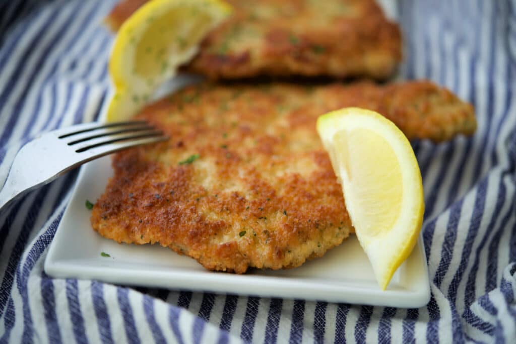 a close up of pork schnitzel on a white plate